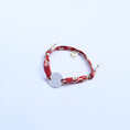 Load image into Gallery viewer, Red floral bracelet with a silver charm on a white background