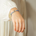 Load image into Gallery viewer, Child wearing a cord bracelet with floral patterns and a silver star pendant