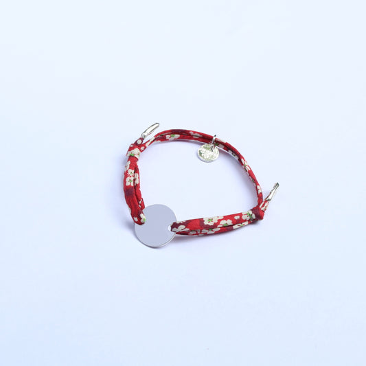 Red floral bracelet with a silver charm on a white background