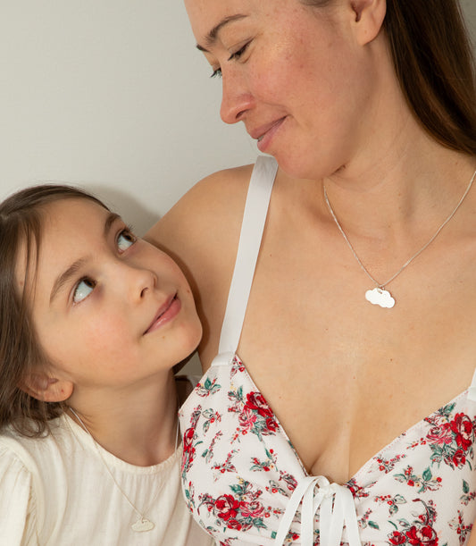Mum and daughter wearing matching necklaces with silver cloud pendants