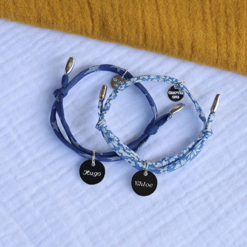 Two cord bracelets with silver pendants, engraved with names 