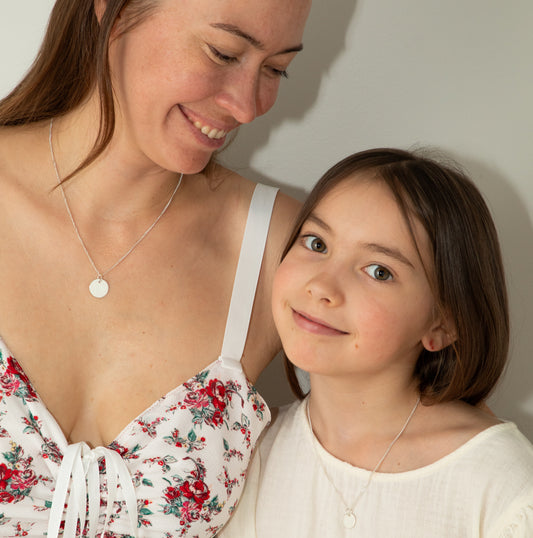 Mother and daughter wearing matching silver necklaces