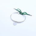 Load image into Gallery viewer, Silver bangle with a green cord and a round charm

