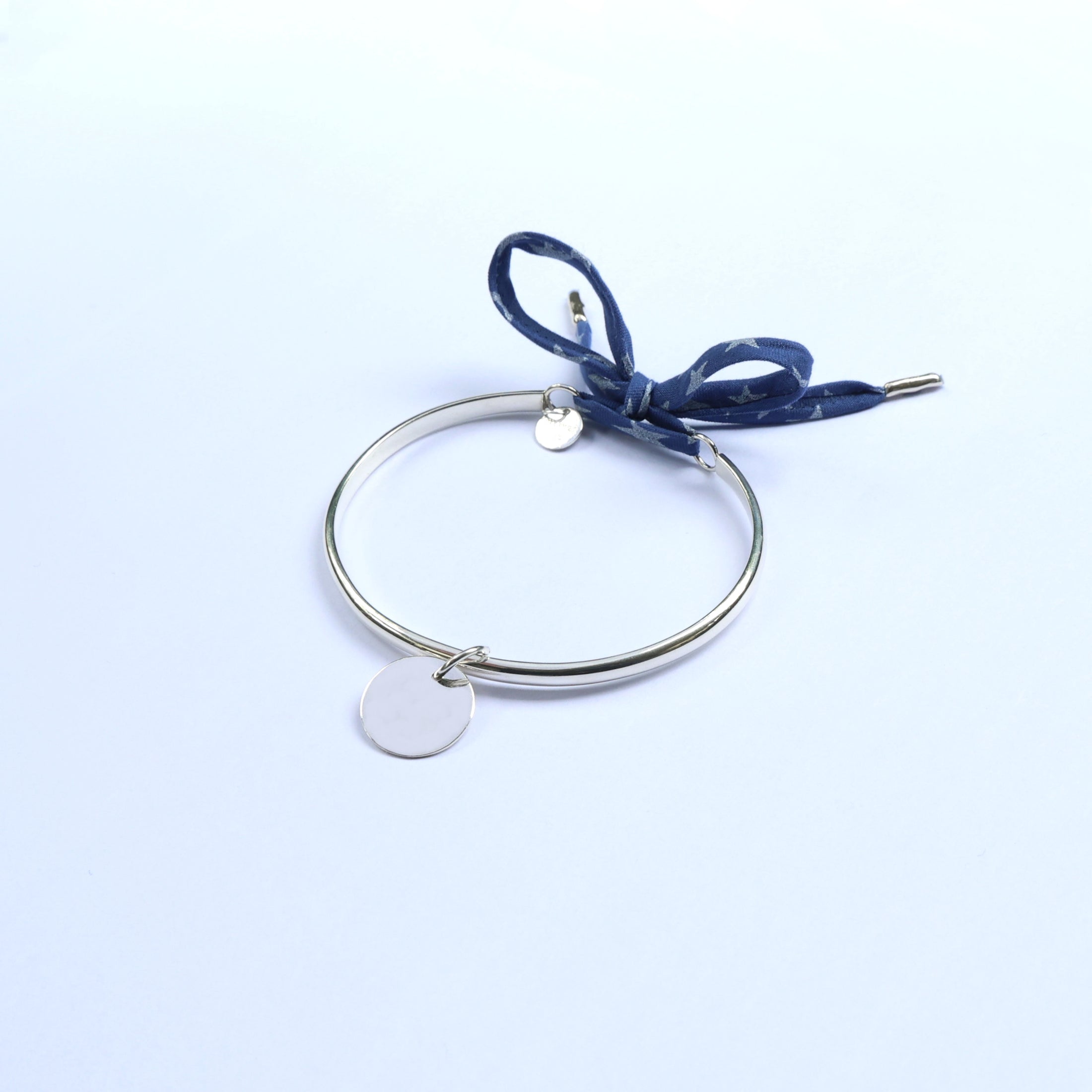 Silver bracelet with engravable round pendants and blue fabric