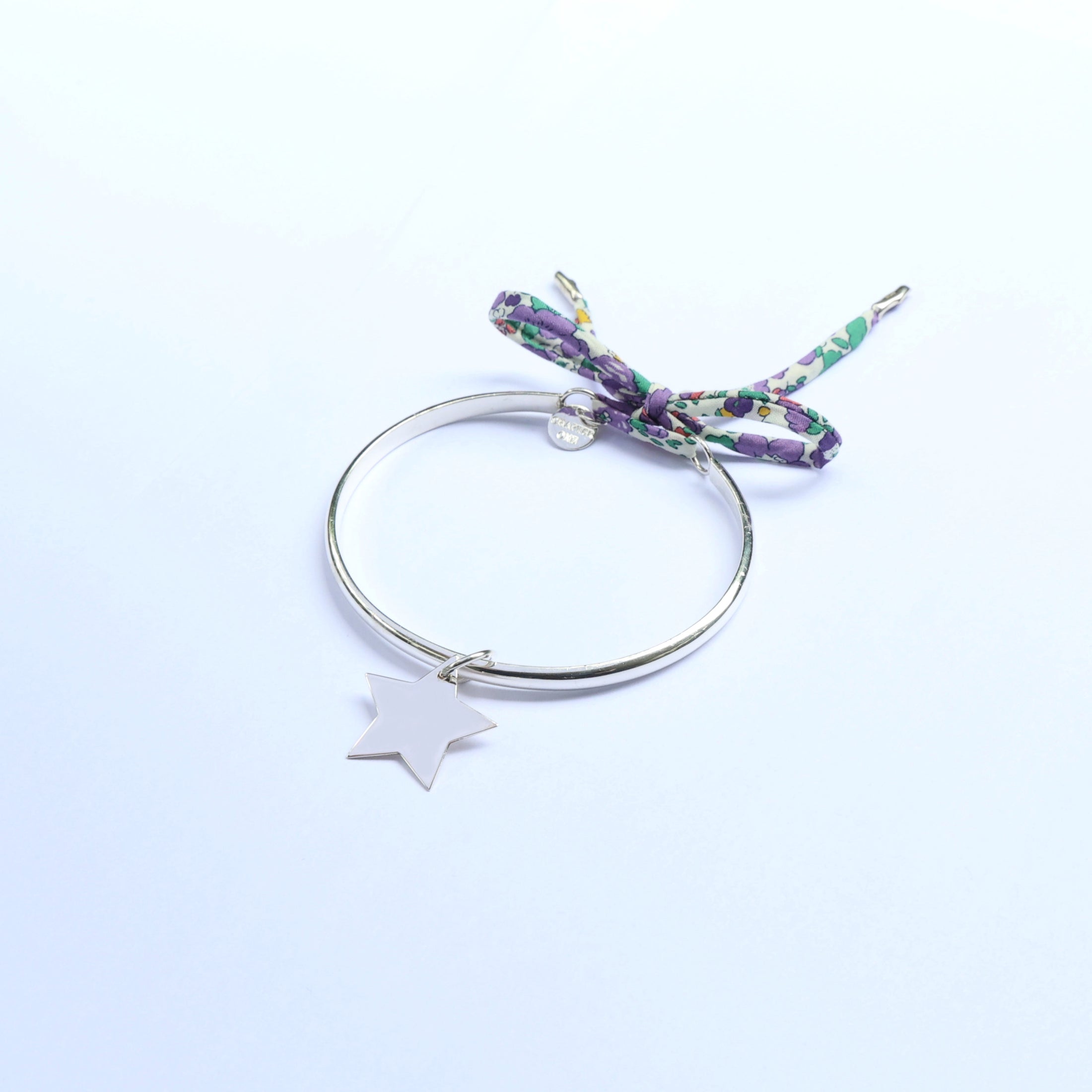 Silver bracelet with a star charm and a floral ribbon